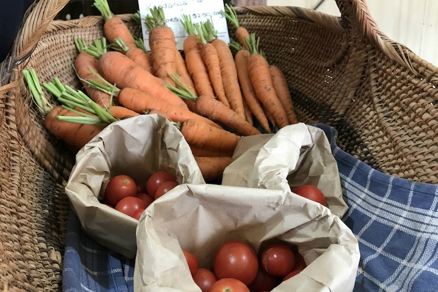 Carrots and cherry tomatoes displayed in a wicker basket.