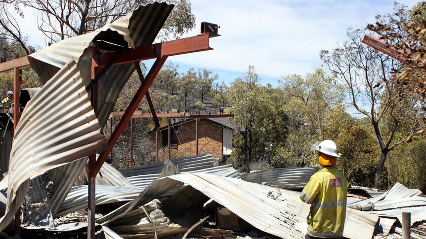 A firefighter stands in the ashes of a razed home