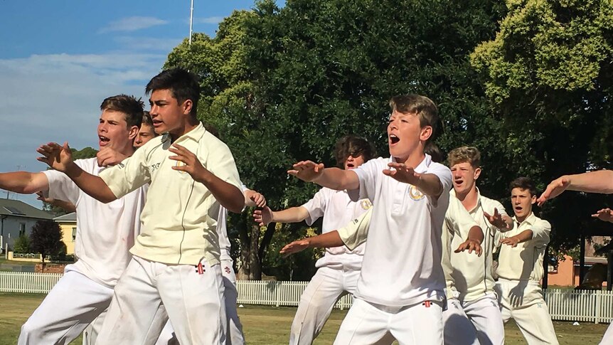 Boys in cricket whites performing the maori haka