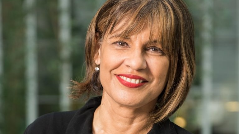 Woman in black suit smiles at camera