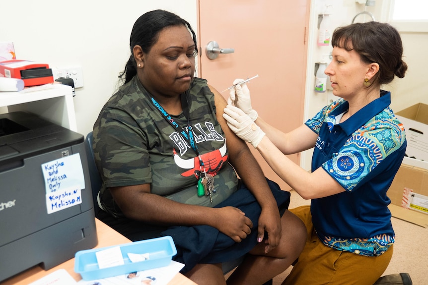 A woman receives a vaccination from a nurse in a clinic