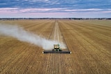 Drone shot of a combine harvester working in a field.