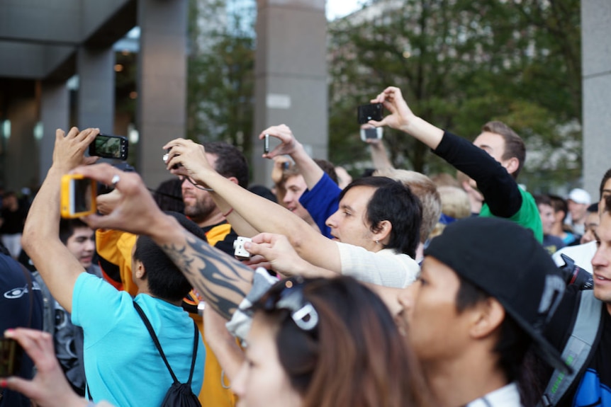 A crowd of people take videos with their smartphones
