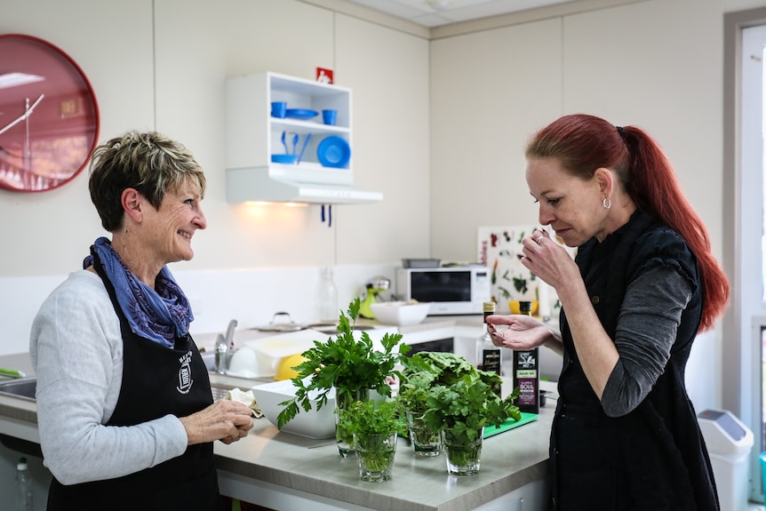 Co-ordinator Michele Witham (left) with parent and student Hope (right) learning about the school's kitchen garden herbs.