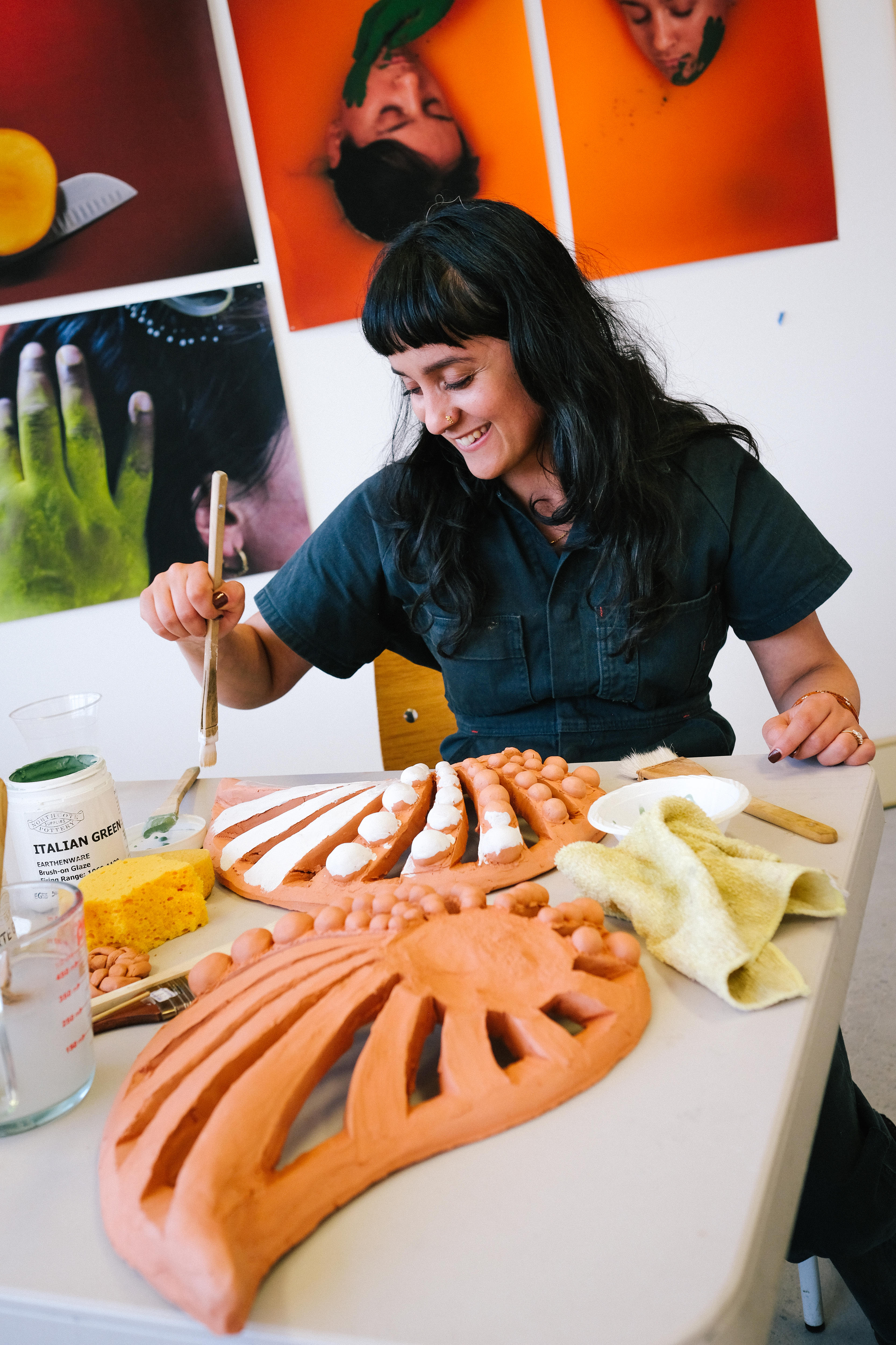 Monica Rani Rudhar painting a sculpture in her studio. She has black hair and brown skin.