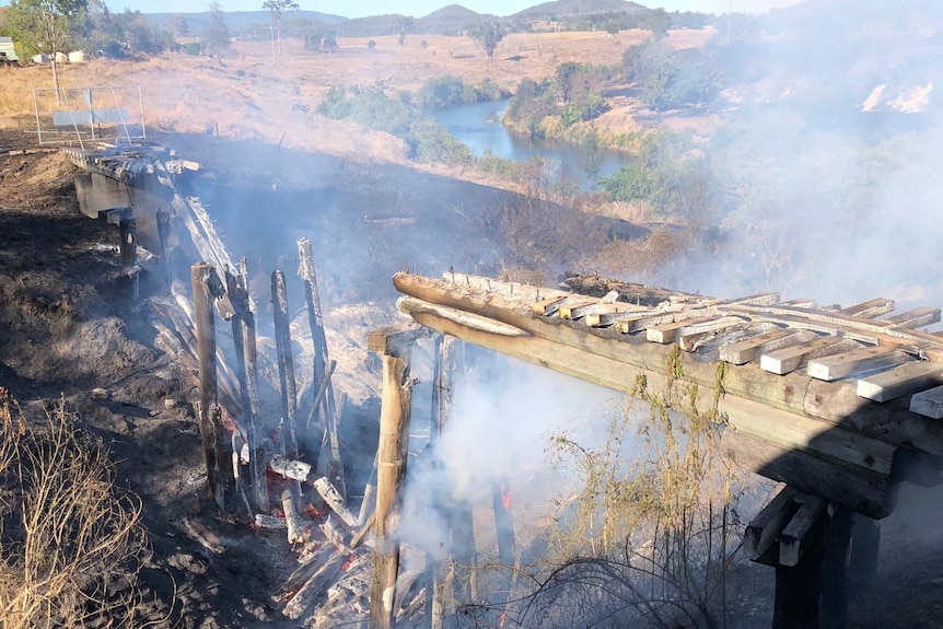 The remnants of a rail bridge fall into a gully after being destroyed by fire.