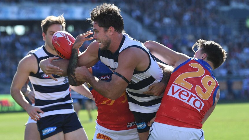 Tom Hawkins of the Cats is wrapped up by the Lions defence.