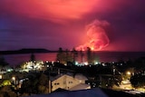 A huge ball of flames and smoke rises in the distance acoss a body of water near Kempsey in NSW