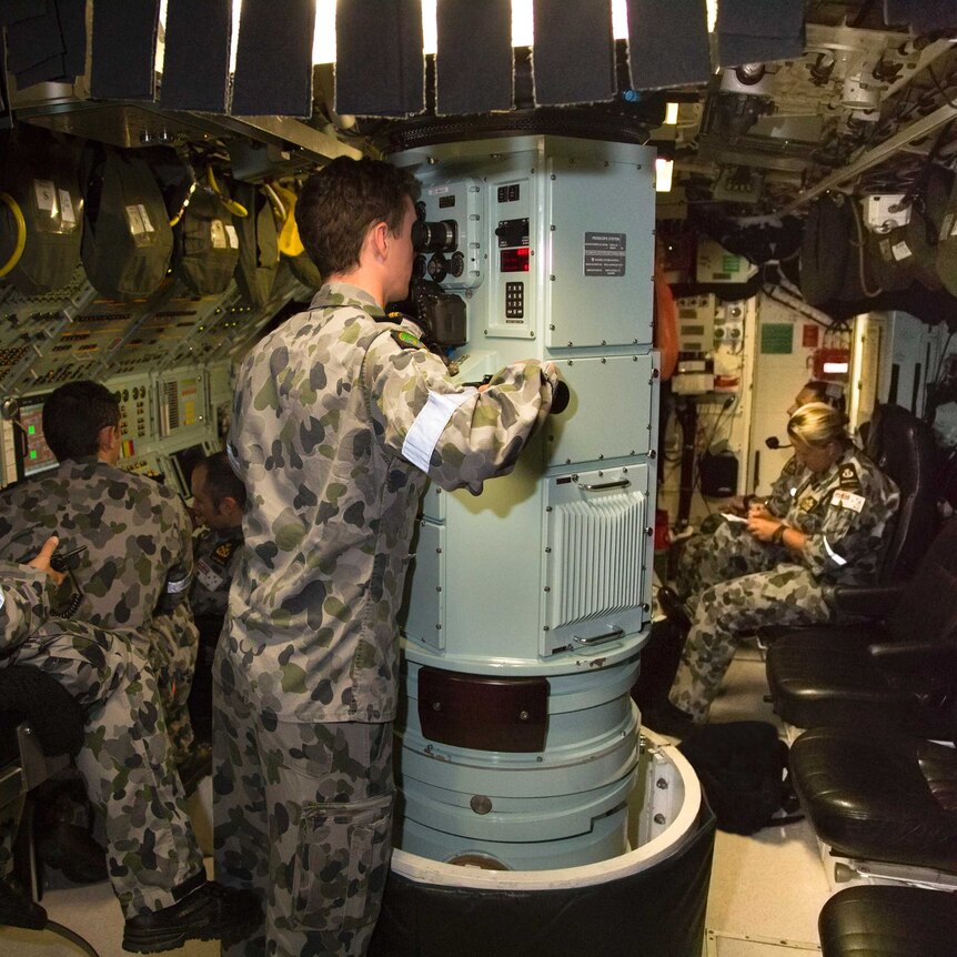Sailors work inside a submarine.