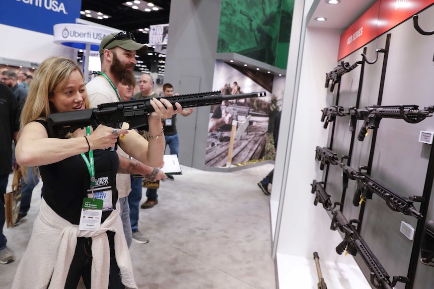 A woman holds an automatic rifle at the 2019 NRA annual meeting