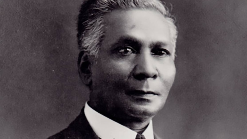 Old black and white studio portrait photo of a middle-aged man wearing a three-piece suit and tie.