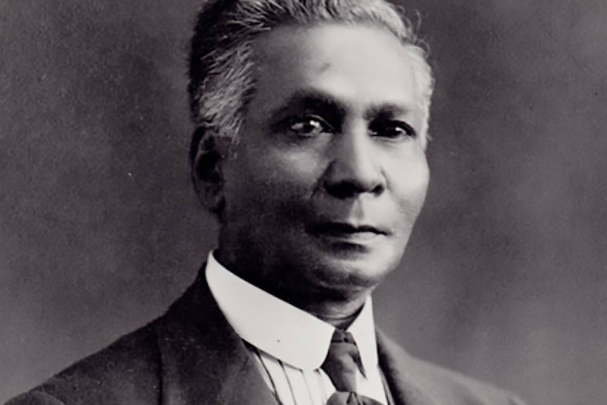 Old black and white studio portrait photo of a middle-aged man wearing a three-piece suit and tie.