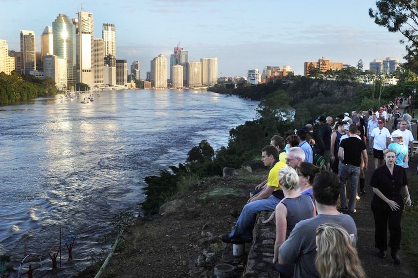 Residents watch the Brisbane River flood peak in the CBD at sunrise at the Kangaroo Point cliffs on January 13, 2011.