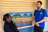 A man in a blue shirt chats to an Indigenous Australian woman