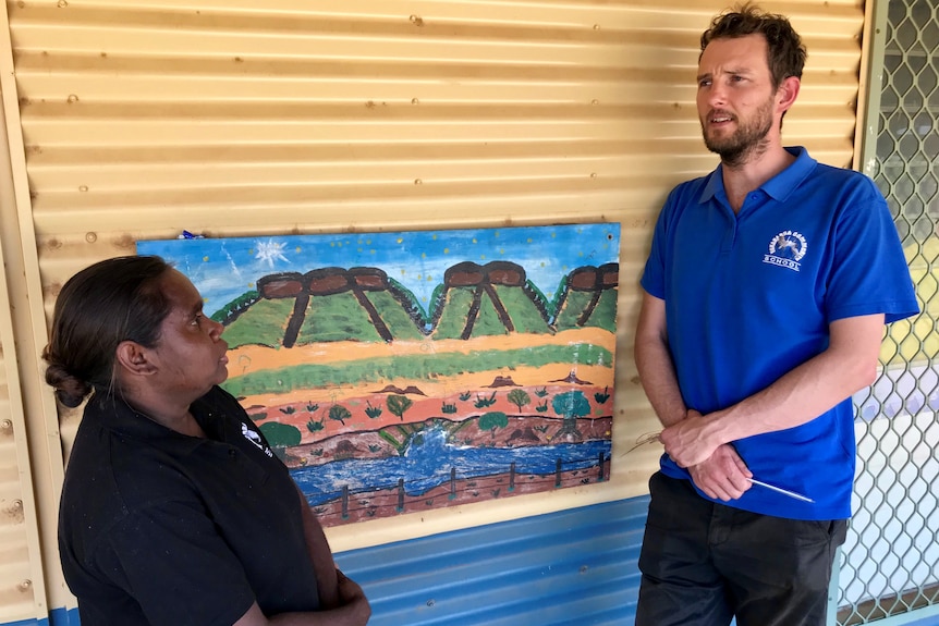 A man in a blue shirt chats to an Indigenous Australian woman
