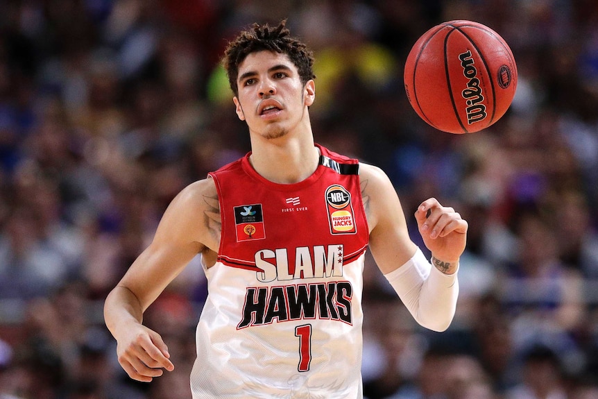 A basketball player looks into the distance with a ball above his hands.