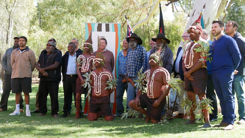 A group of mostly Indigenous men pose and smile while their photo is taken. Two of the men are on their knees in front. 