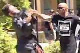 A wide still frame from television footage showing Mark Musa Bhatti attacking an ABC reporter with an outstretched hand.