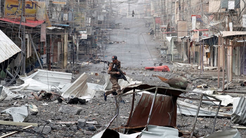 An Iraqi special forces soldier runs across a street.