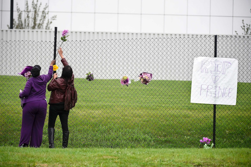 Prince fans leave flowers outside Paisley Park next to a sign remembering Prince.