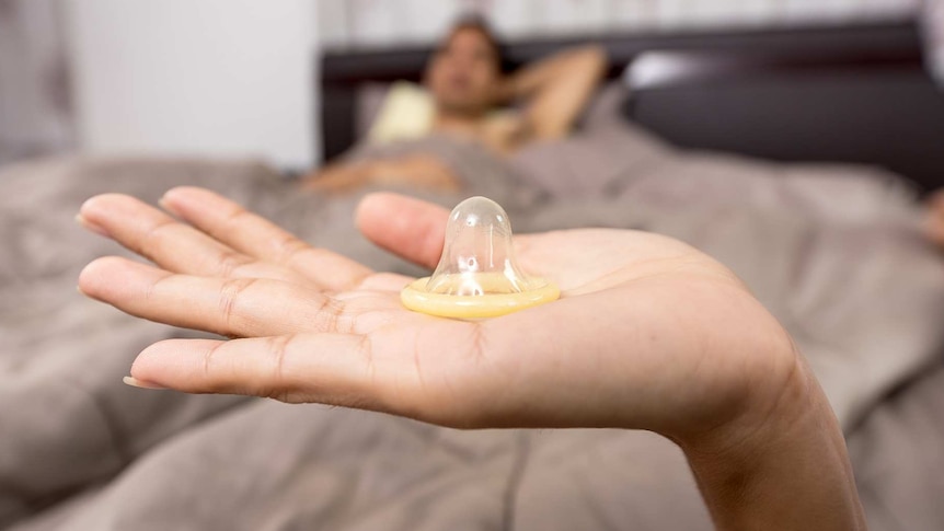 A woman's hand holding a condom