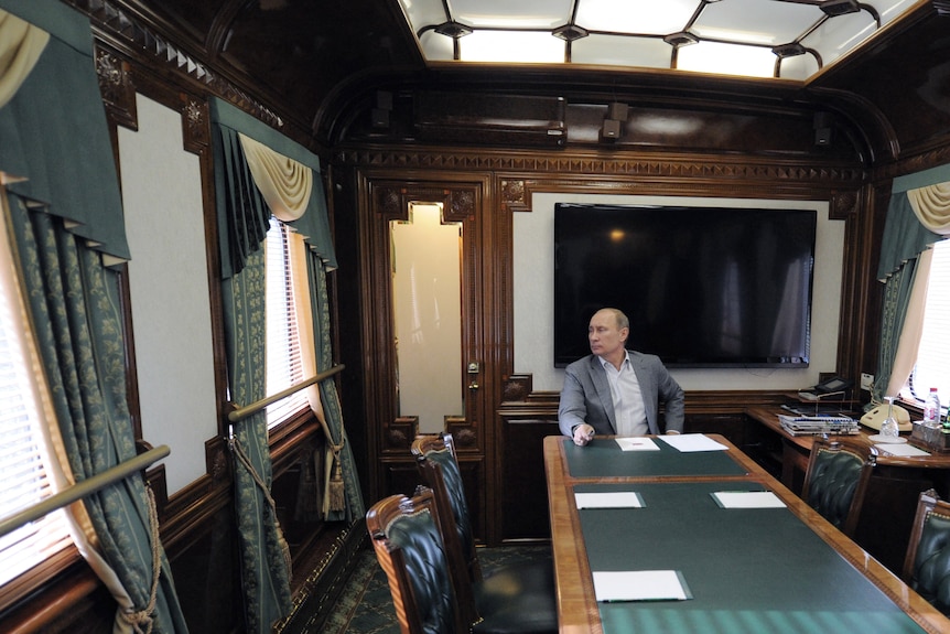 Russia's President Vladimir Putin looks in the windows of his railway car as he sits inside a train.