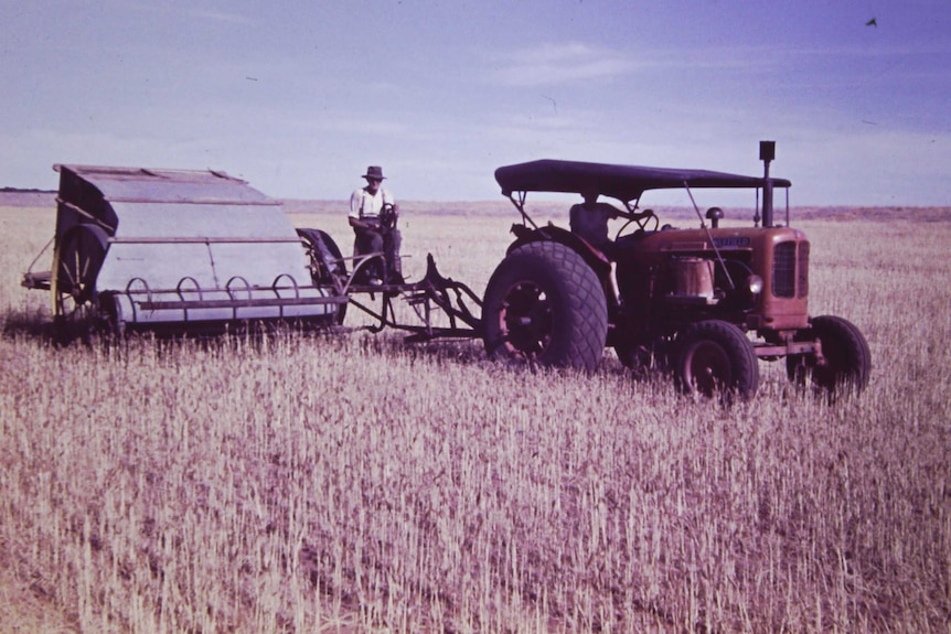 An old picture of a tractor and harvester in field