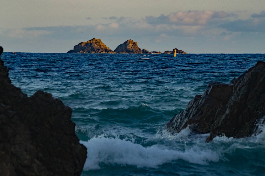 A blue sea surrounds a rocky island