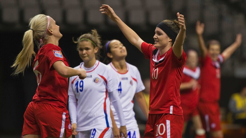 Kaylyn Kyle and Christina Julien prepare to hug each other after a goal was scored in a football international.