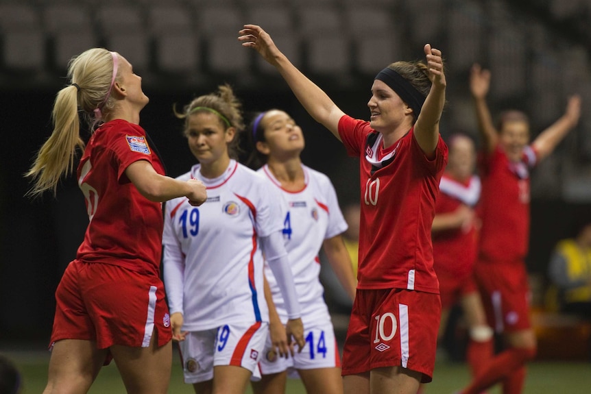 Kaylyn Kyle and Christina Julien prepare to hug each other after a goal was scored in a football international.