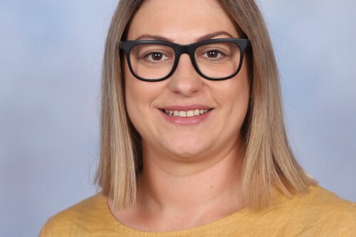 head shot of woman with blonde hair in yellow top and glasses