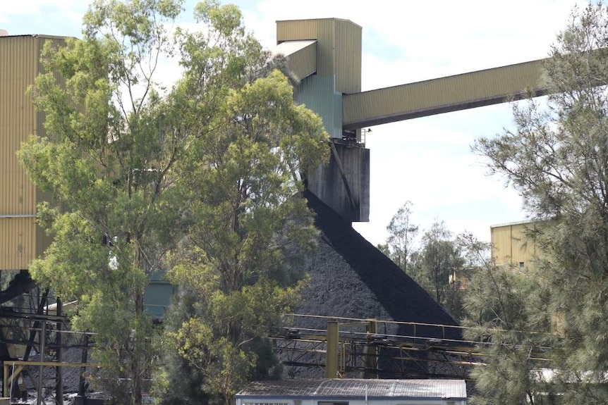 Coal mine infrastructure with trees in the foreground.