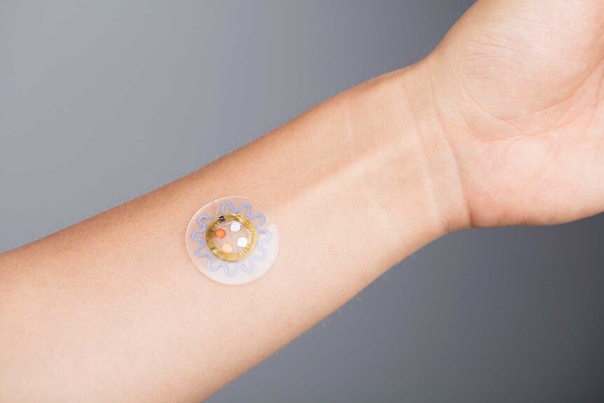 A circular patch with electronics inside it, stuck onto someone's inner-wrist