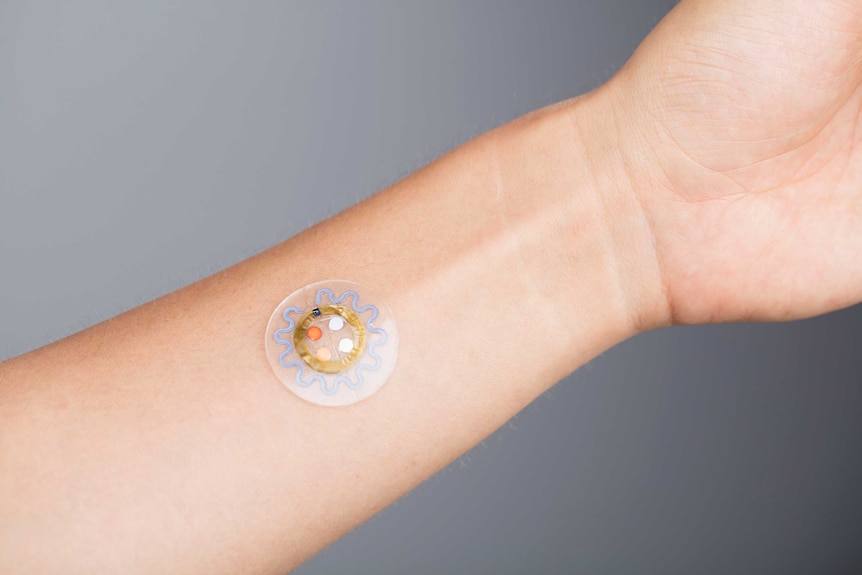 A circular patch with electronics inside it, stuck onto someone's inner-wrist