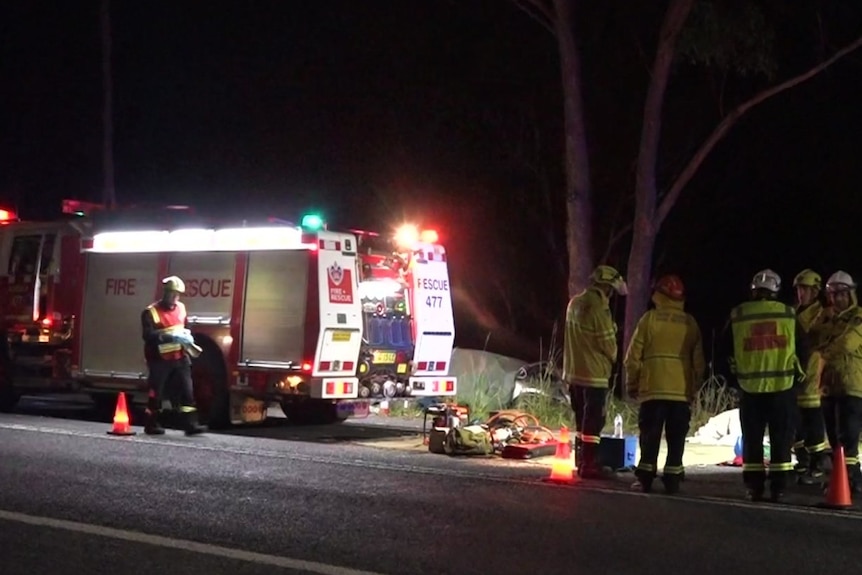 An ambulance and emergency service personnel on a road at night.