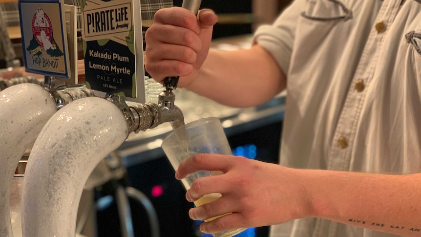 A man pours a beer into a glass from a beer tap