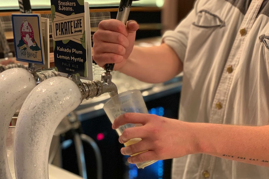 A man pours a beer into a glass from a beer tap