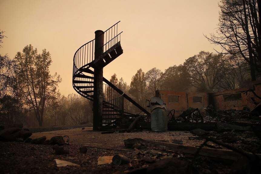 A spiral staircase stands in the remains of a burned out home from the Camp Fire.