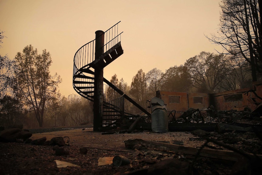A spiral staircase stands in the remains of a burned out home from the Camp Fire.
