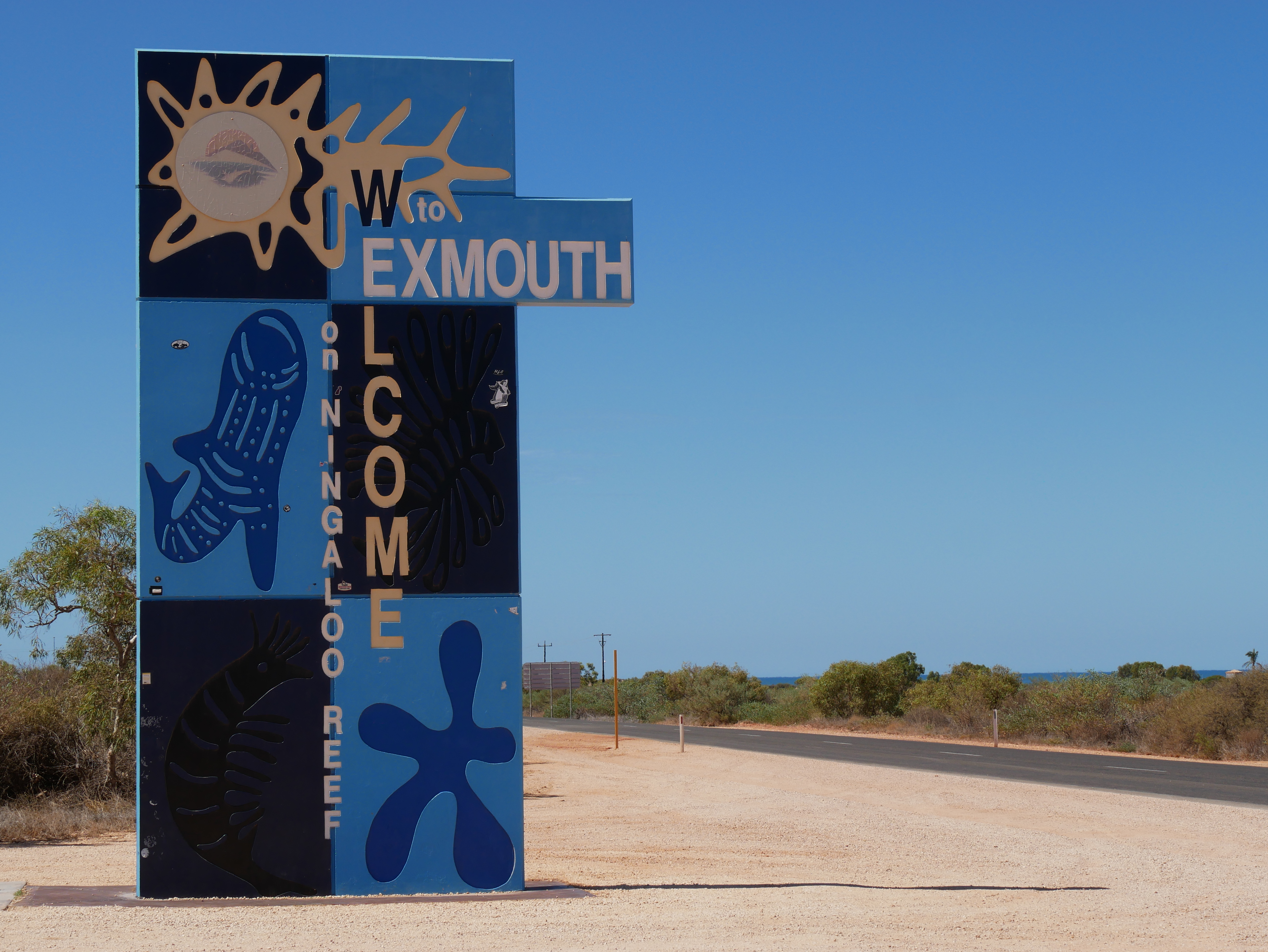 A blue sign with abstract images of marine life and a whale shark, with large yellow text written vertically.