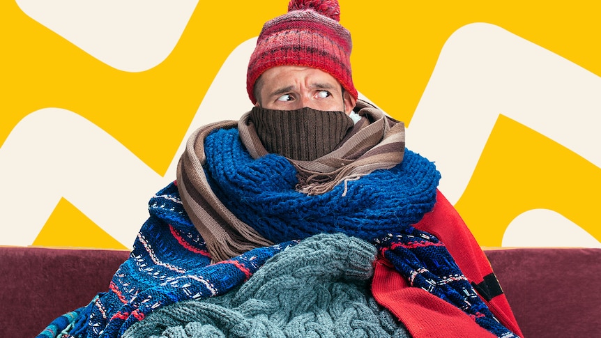 A man is rugged up with blankets and a beanie.