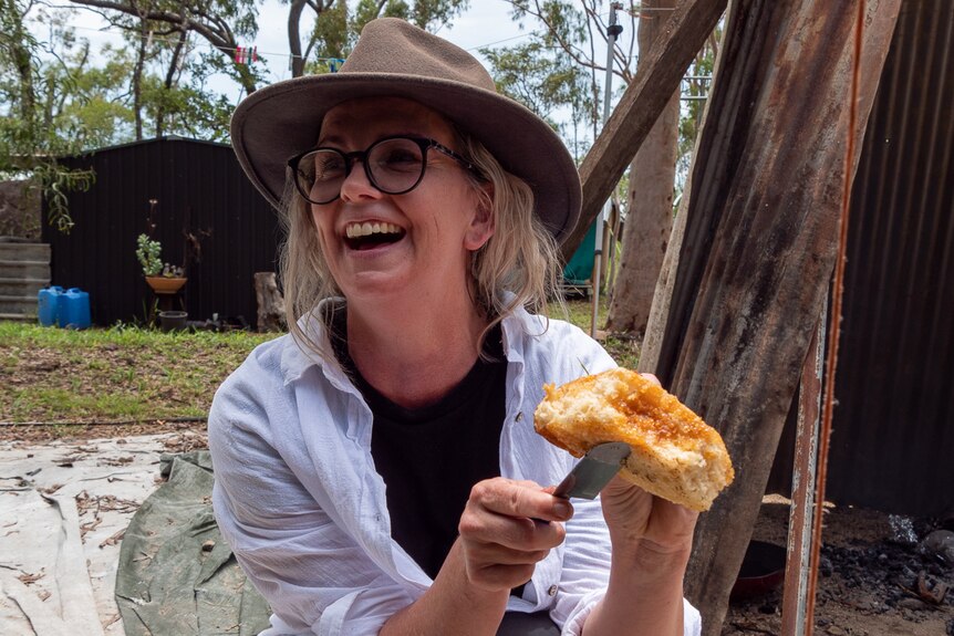 woman in hat and white shirt holding piece of damper glazed with bush cherries.