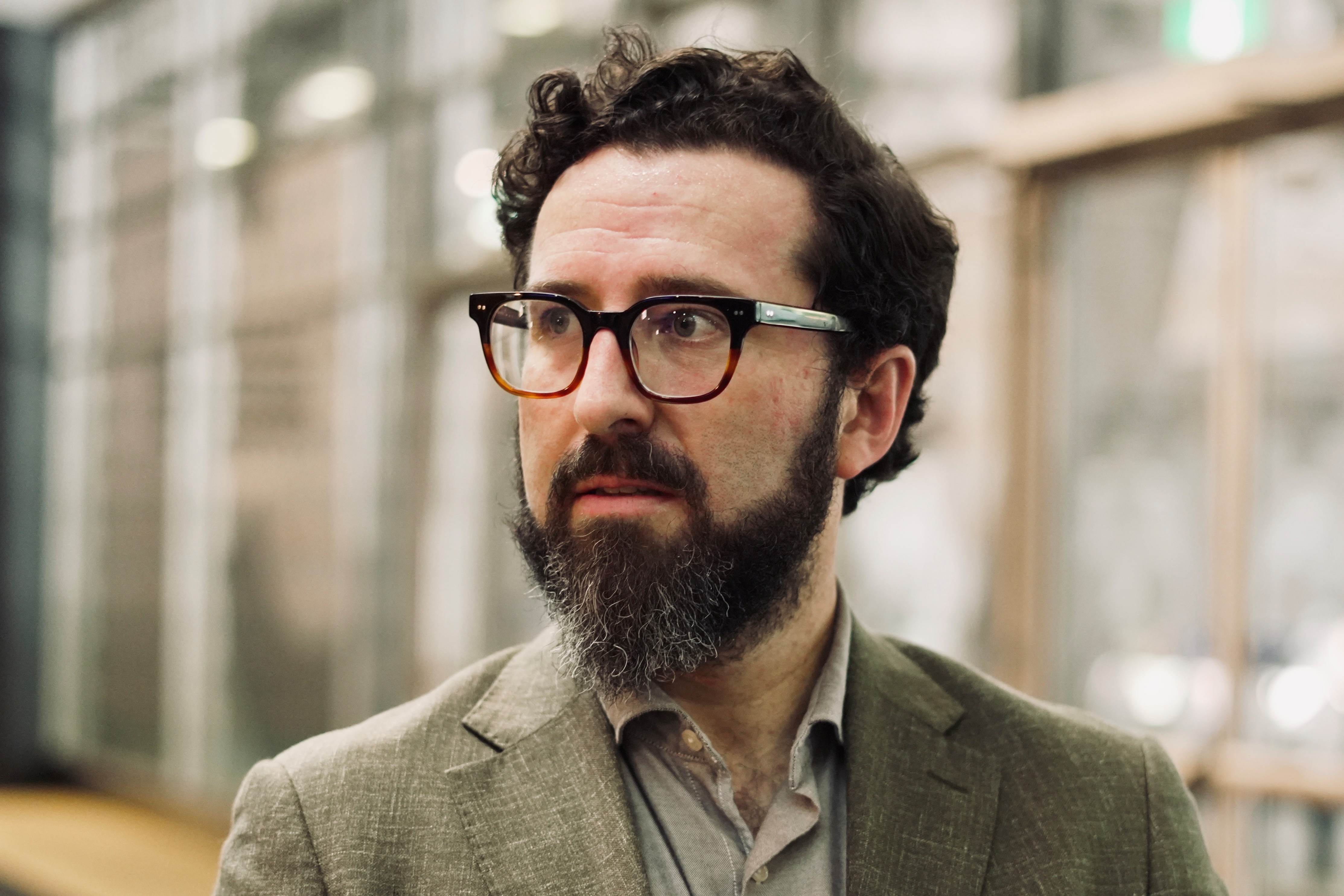 A dark-haired, bearded man in glasses and a sports coat.