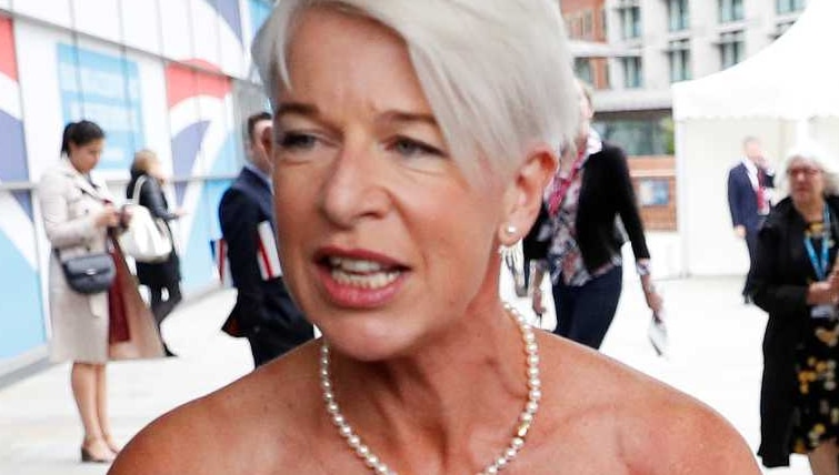 Woman with short grey hair wears wedding dress outside public building