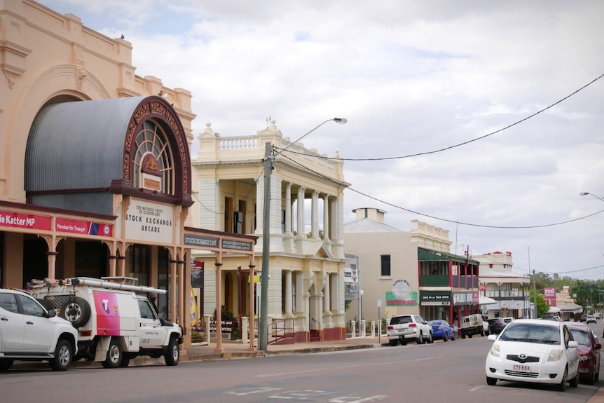 A photo of a streetscape with old heritage buildings, cars parked in front.