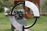 A circular shaped aluminium and black sculpture in a sculpture garden