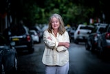 A woman stands arms crossed on a Sydney street. Cars in background