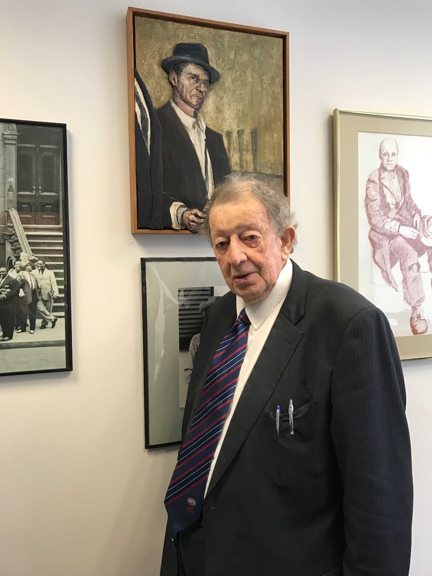 Brian Bourke stands next to a painting of Ronald Ryan.