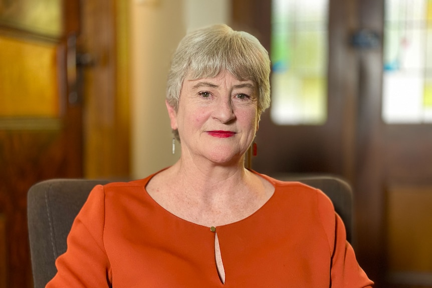 A woman wearing orange smiles at the camera.