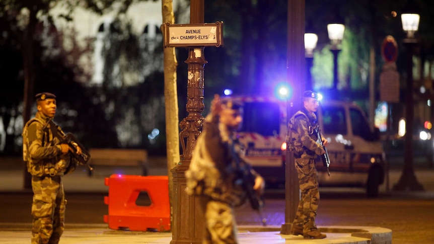 French soldiers with machine guns stand on the Champs Elysees